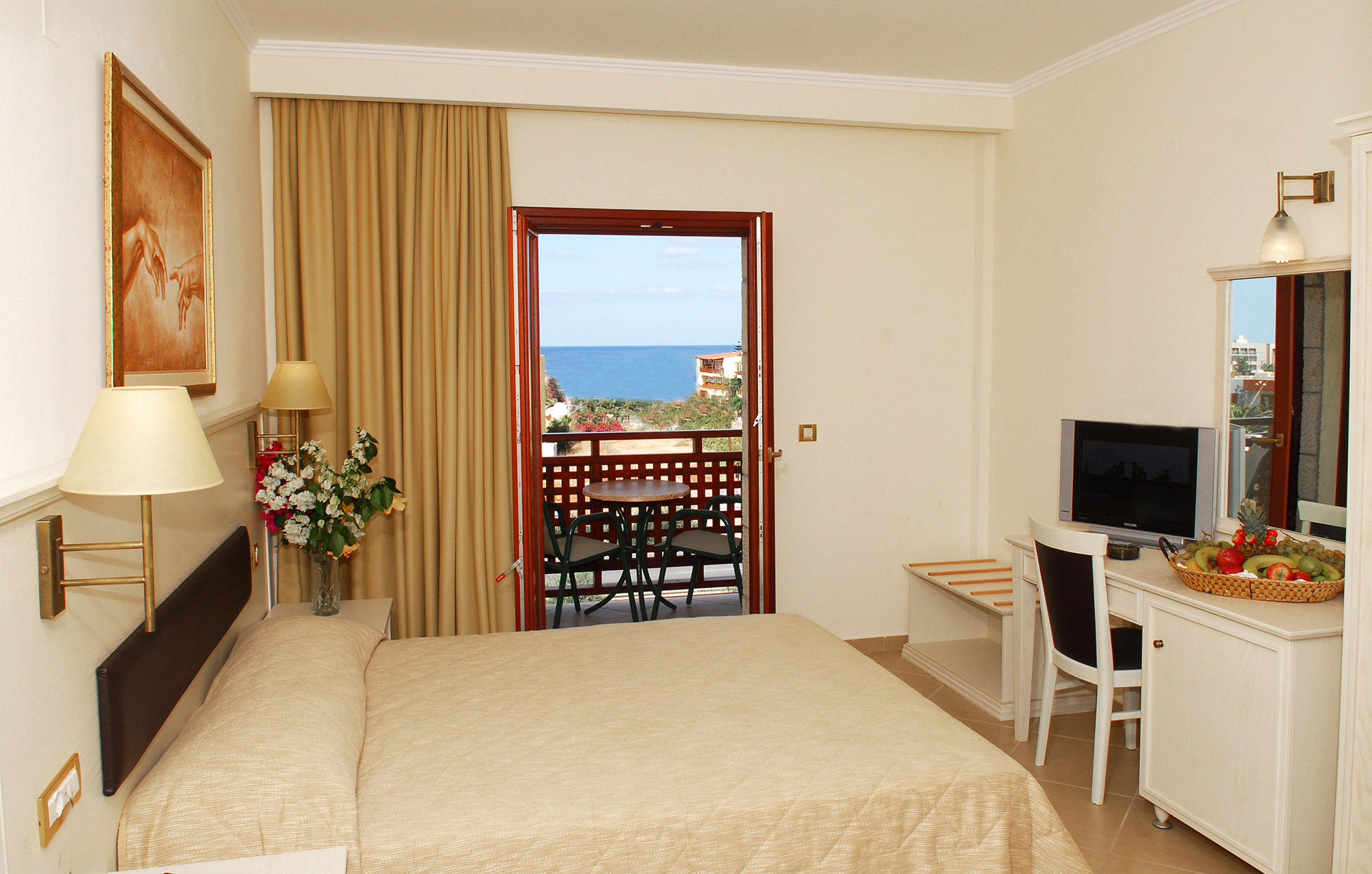 Cactus village hotel room with a double bed, a TV and a balcony overlooking the sea